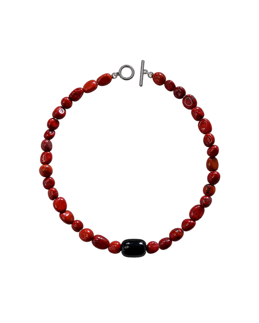 A beaded bracelet made of glossy red beads with a single black bead accent and a silver toggle clasp, shown on a plain white background.