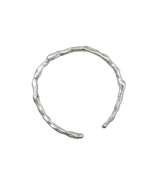A textured, organic-shaped silver cuff bracelet on a plain white background.