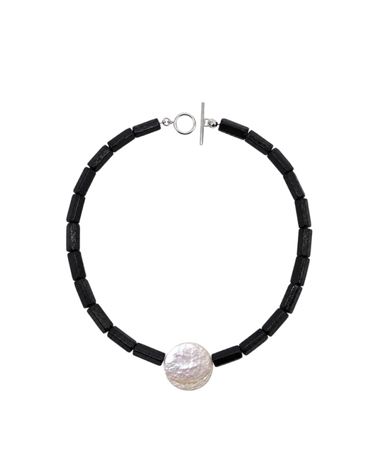 A black tourmaline rough beaded necklace with a textured white pearl pendant and a silver toggle clasp, displayed on a clean white background.